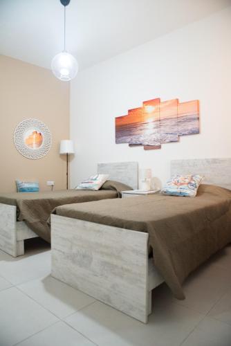 a bedroom with two beds and a painting on the wall at Sun Sea Living Gozo (Seagull) in Xlendi
