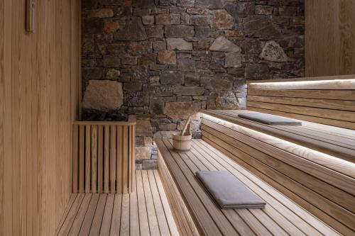 a sauna with wooden benches and a stone wall at Acro Suites - A Wellbeing Resort in Agia Pelagia