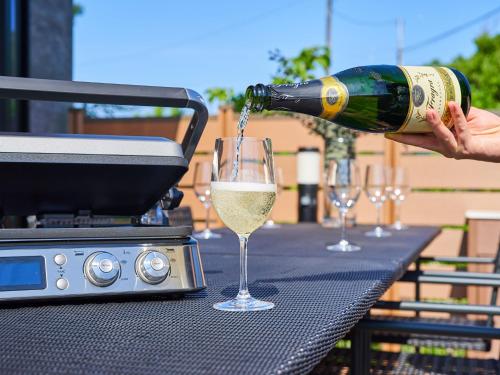 a person pouring white wine into a glass on a grill at Rakuten STAY HOUSE Kujukuri Ichinomiya in Ichigaya