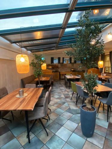 ウッテンドルフにあるScharler's Hotelの木製のテーブルと椅子、鉢植えの植物があるレストラン