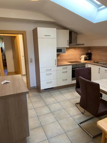 a kitchen with white cabinets and a table and chairs at Hotel in the HEART of the Alps in Uttendorf
