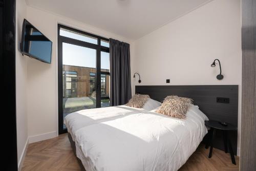 a bedroom with a white bed and a large window at MarinaPark Residentie Nieuw Loosdrecht in Loosdrecht