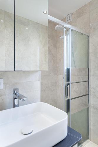 une salle de bain avec un lavabo blanc et une douche dans l'établissement Les appartements de Chantilly - gare, à Chantilly