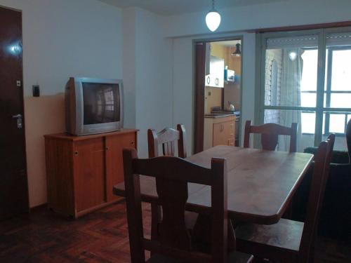 une salle à manger avec une table en bois et une télévision dans l'établissement 2 Departamento pleno Centro todo equipado, à Córdoba