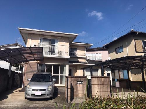 une voiture garée devant une maison dans l'établissement 花源, à Beppu