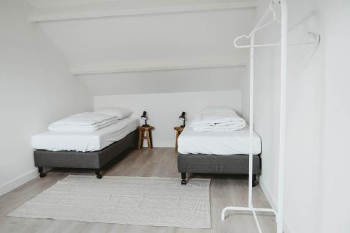 - 2 lits dans une chambre avec des murs blancs et un miroir dans l'établissement Villa Bandi - Group & Family House, à Lanaken