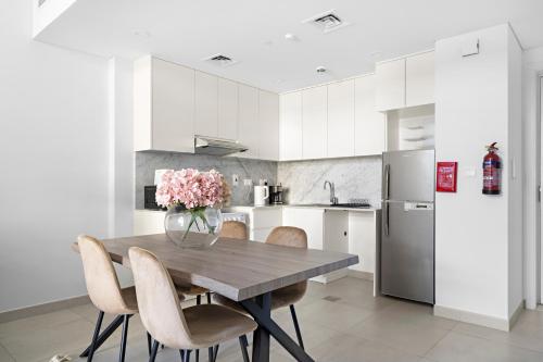 a kitchen with a wooden table with chairs and a vase of flowers at Stylish 1BR Apt Umm Suqeim 3 in Dubai