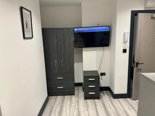 a room with a tv on a wall with a cabinet at Studio apartment in Catford