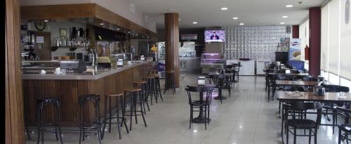 a restaurant with a bar with stools in the middle at Hotel Costa Blanca in Granja de Rocamora