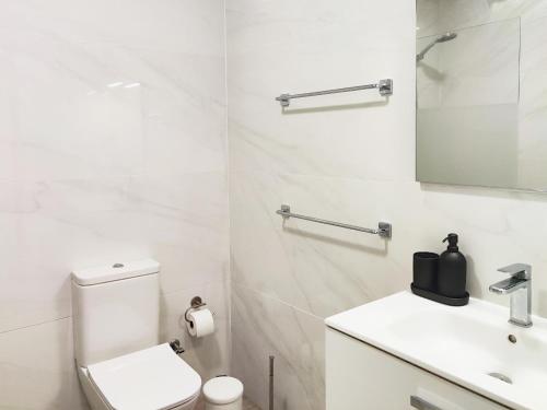 Baño blanco con aseo y lavamanos en Elegant apartment with private workspace, en Candelaria