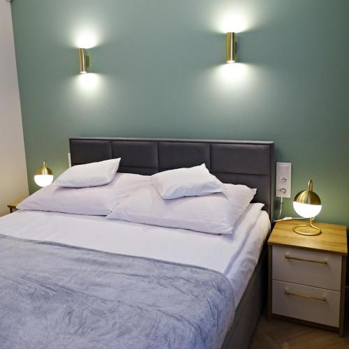 a bedroom with a bed with two lights on the wall at Apartamenty u ROXI in Jelenia Góra