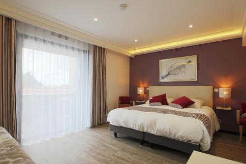 a bedroom with a bed and a large window at Le Clos du Moulin in Vaudemanges