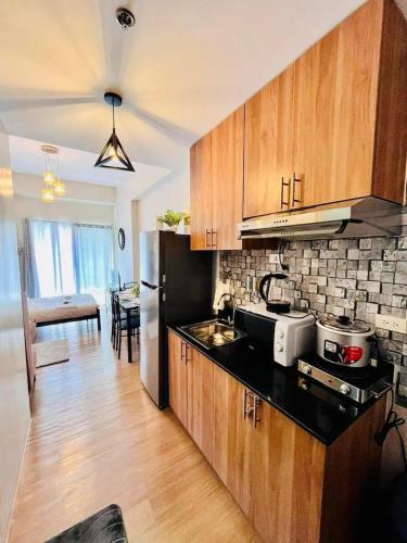 eine Küche mit Holzschränken und einem schwarzen Kühlschrank in der Unterkunft Serenity Stay Condo at 19th floor The Loop Tower Limketkai Center Lucky 19 in Cagayan de Oro