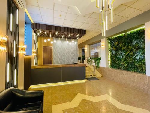 un vestíbulo con una zona de espera con plantas en las paredes en Tengri Hotel en Atyraū
