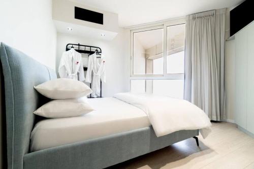 a bedroom with a bed with pillows and a window at Sweet Love - דירה מהממת על הטיילת בבת ים עם נוף מושלם in Bat Yam