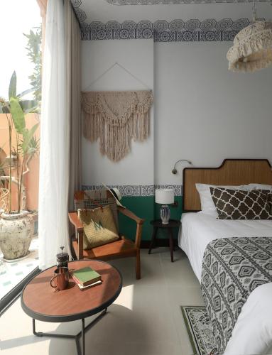 a bedroom with a bed and a table and a chair at The Mansion Hoi An by Minova in Hoi An