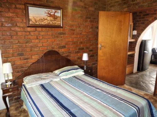 a bed in a room with a brick wall at Serendipity self catering one bedroom apartment in Despatch