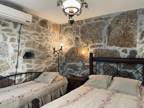 um quarto com 2 camas e uma parede de pedra em Quinta Do Moinho Turismo de Natureza em Aldeia Viosa