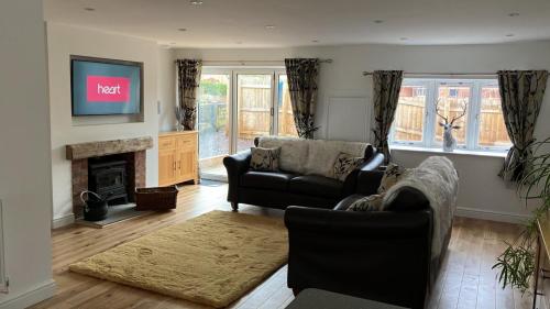 a living room with two couches and a flat screen tv at Honeysuckle Cottage -PART OF ALTON COTTAGES in Alton