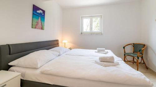 a bedroom with a large white bed with a chair at 100 Meter zur kristallklaren Adria in Baška