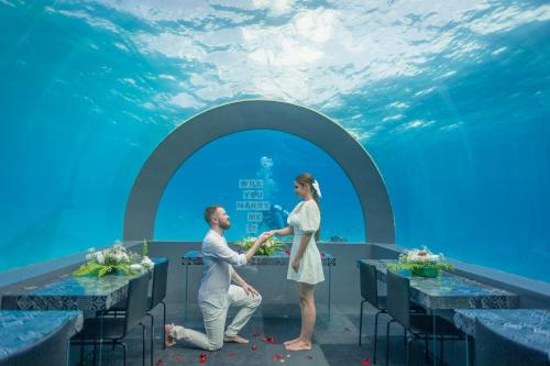 a man and a woman standing at a table in an aquarium at You & Me Maldives - Adults Only - Premium All-Inclusive in Raa Atoll