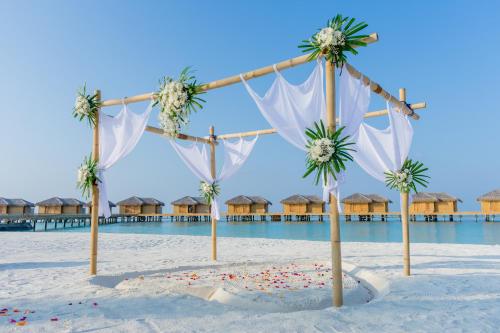 a wedding arch on the beach with overwater bungalows at You & Me Maldives - Adults Only - Premium All-Inclusive in Raa Atoll