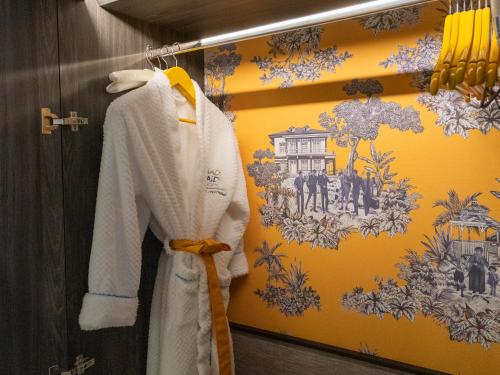 a white robe is hanging on a wall at Madi Paidi Bangkok, Autograph Collection in Bangkok