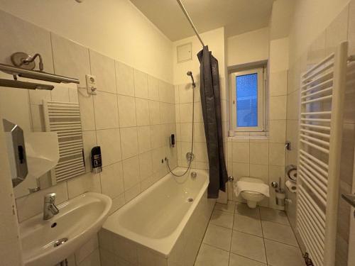La salle de bains est pourvue d'une baignoire, d'un lavabo et de toilettes. dans l'établissement WestEnd#206, à Francfort-sur-le-Main