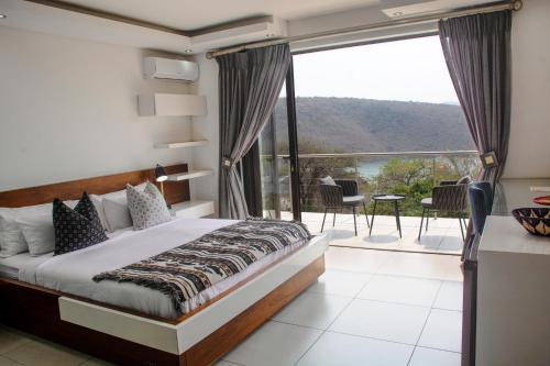 a bedroom with a bed and a balcony with a view at Impecto Guest House in Jozini