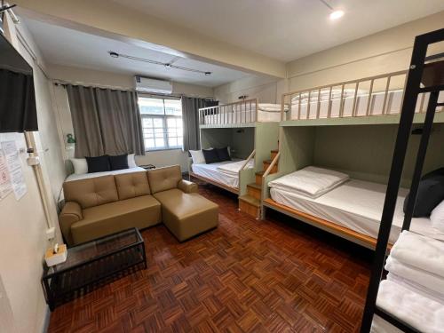 ein kleines Zimmer mit 2 Etagenbetten und einem Sofa in der Unterkunft Achcha Family Hotel in Bangkok