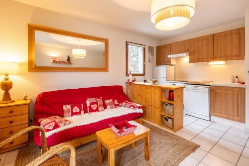 un salon avec un canapé rouge dans une cuisine dans l'établissement Le Refuge du Chevreuil - Pistes accessibles, aux Angles