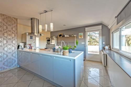 une grande cuisine avec des placards bleus et une grande fenêtre dans l'établissement Ty Kap - Maison 4 chambres vue mer, à Plougastel-Daoulas