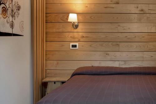 a bedroom with a wooden wall with a bed at Piccolo Hotel Aurora in Abbadia San Salvatore