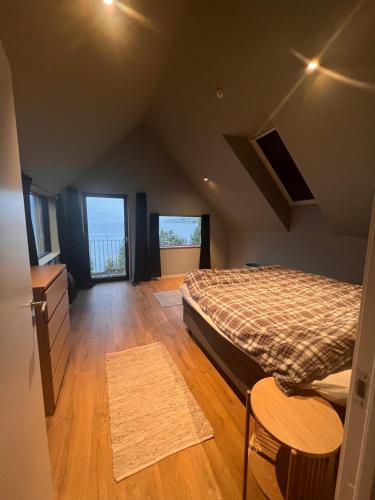 ein Schlafzimmer mit einem Bett, zwei Fenstern und einem Holzboden in der Unterkunft Modern house by the Fjord in Sandane, Nordfjord. in Sandane