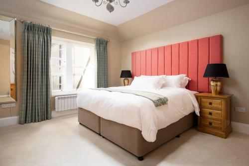 a bedroom with a large bed with a red headboard at The Scott Apartment in Kelso