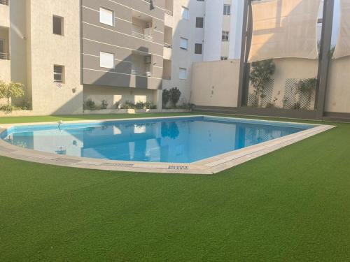 a swimming pool in front of a building with green grass at AGORAMI in Nabeul