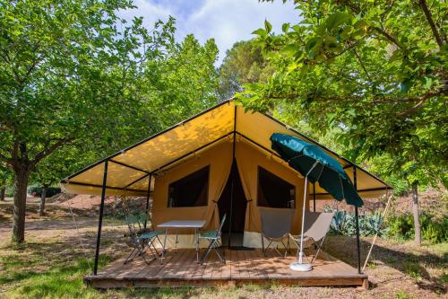 Tienda de campaña con sillas y sombrilla en un campo en CAMPING ONLYCAMP LE PORT en Saint-Benoît-sur-Loire