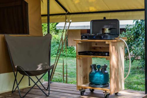 einen Stuhl auf einer Veranda mit einem Tisch und einem Kühlschrank in der Unterkunft CAMPING ONLYCAMP LE PORT in Saint-Benoît-sur-Loire