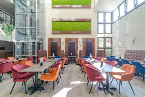 a restaurant with tables and chairs and windows at Wellness Hotel Katalin in Gyenesdiás