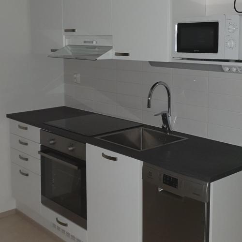 eine Küche mit einer Spüle und einer Mikrowelle in der Unterkunft Cozy Studio in Espoo NEW in Helsinki