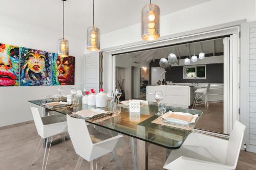 une salle à manger avec une table en verre et des chaises blanches dans l'établissement Grand Case - Villa chic 6p 3ch 3sdb Vue panoramique, à Saint Martin