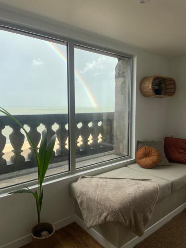 asiento junto a la ventana con arco iris en una habitación en La vigie Malouine - Front de mer, en Dunkerque