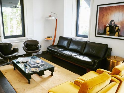 a living room with a black leather couch and chairs at Bonvalot Guest House in Paço de Arcos