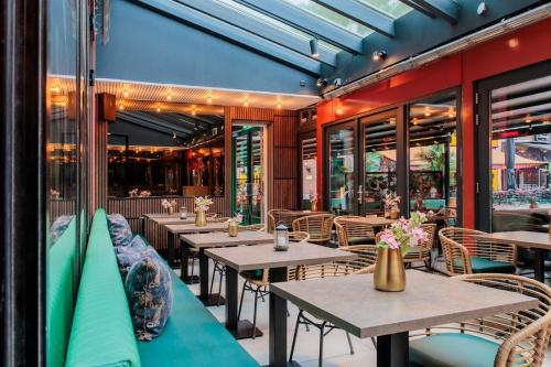 un restaurante con mesas y sillas de madera y ventanas en Monument Hotel, en Zaandam