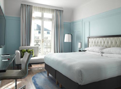 a bedroom with a bed and a desk and a window at Paris Marriott Opera Ambassador Hotel in Paris