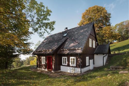 a black and white house with a red door at Chaloupka Dvě Sestry in Kořenov