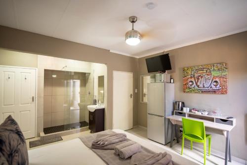 um quarto com uma cama, um lavatório e um frigorífico em Meadowbrook Guesthouse em Pretoria