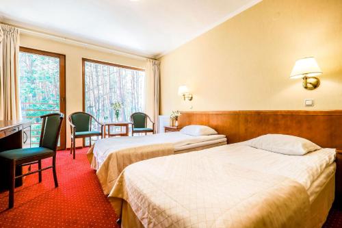 una camera d'albergo con due letti e un tavolo con sedie di Hotel Magellan a Bronisławów
