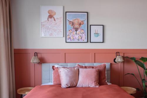 a bedroom with a pink bed with four pictures on the wall at TurnKey I Letná Park Apartments in Prague