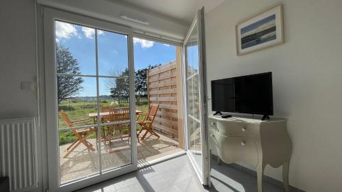 een woonkamer met een televisie en een glazen schuifdeur bij Maison vue sur la Baie de Canche in Étaples